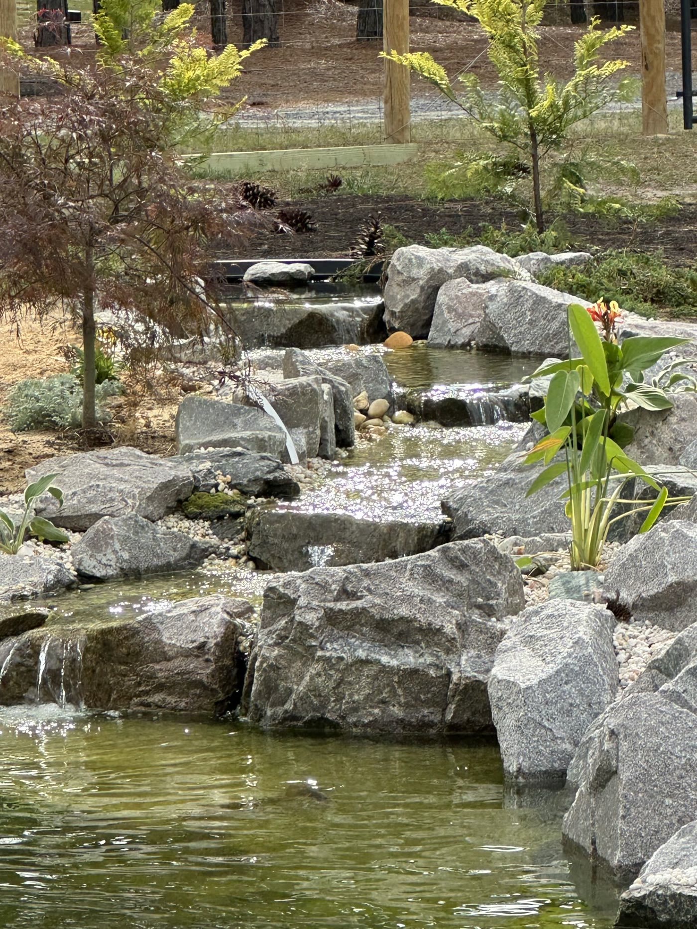 Natural stone waterfall and stream flowing into a pond