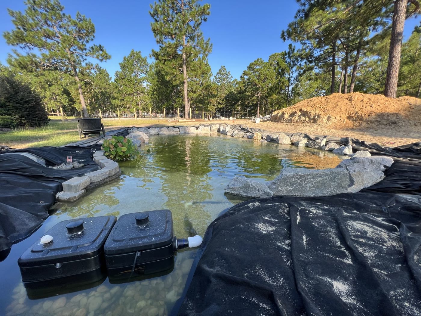 Wide residential ecosystem pond with rock edges and clear water